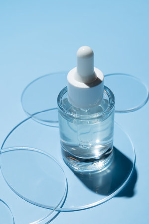Serum with pipette in petri dish on blue background. Top view, flat lay. Dermatology science cosmetic laboratory. Natural medicine, cosmetic research, organic skin care products.の写真素材