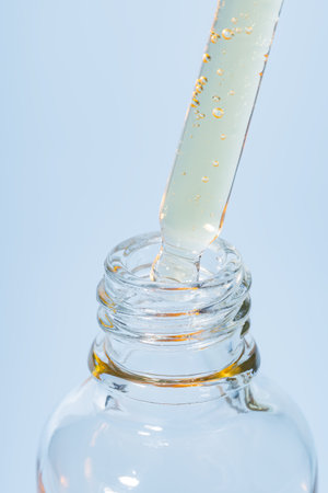 macro shot of serum dropper pipette and pouring retinol beauty serum on blue. Skin care treatment presentation. texture of the productの写真素材