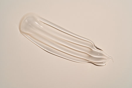 Squeezed cosmetic clear cream gel texture Isolated on beige background. Close up transparent serum drop smear.の写真素材