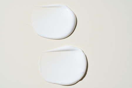 Texture of white cream on beige background. Smear of moisturizer close up. Lotion swatch. Beauty skin care product smear smudge. SPF sunscreen cream sample on beigeの写真素材