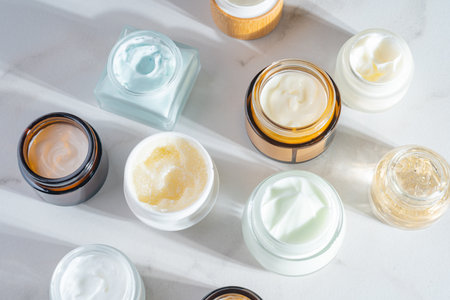 Cosmetics packaging. Set of different cosmetic jars of face cream, mask, balm on beige marble...