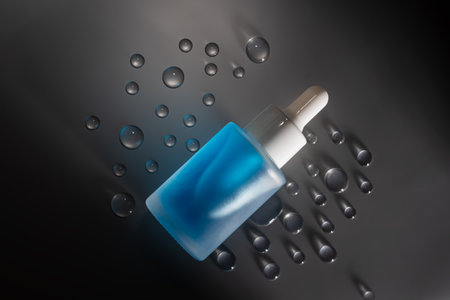 blue dropper bottle with serum on grey with waterdropsの写真素材