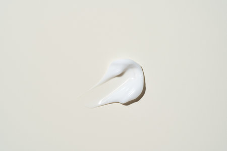 A smooth stroke of cream on a soft beige background, showing its rich texture for skincare product displaysの写真素材