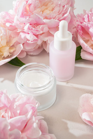 Skincare product display with cream jar, serum bottle and peony accent, ideal for e-commerce visuals, beauty shop catalogs and product showcase content.の写真素材