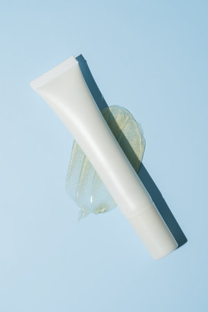 White cosmetic tube with gold-shimmer cream smear on sleek surface. Luxurious texture shot for high-impact beauty branding and premium product visuals.の写真素材