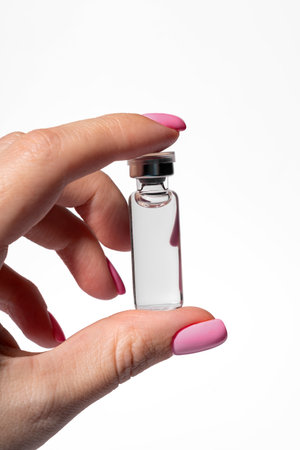 Professional hand holding cosmetic ampoule with serum or peeling in salon setting skincare treatment closeupの写真素材