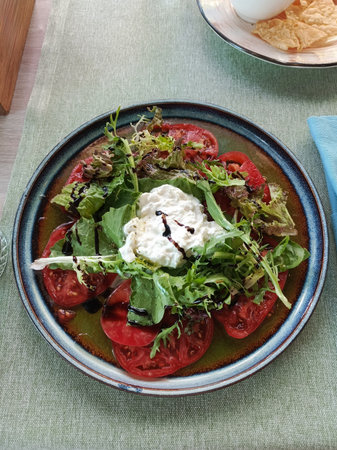 Top view of fresh Stracciatella salad with ripe tomatoes and olive oil drizzle rustic Italian appetizer flat layの写真素材