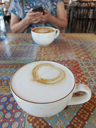 Artisan latte in ceramic cup on rustic table with tile surface morning coffee photographyの写真素材