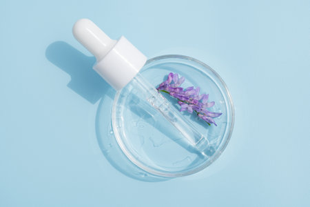Cosmetic pipette serum on a petri dish on blue background. Cosmetology and pharmaceuticals concept....