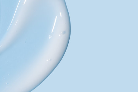 White cosmetic cream texture on blue background. Skin care product smear. Lotion, hair mask or other cosmetic product texture with copy spaceの写真素材