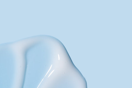 Texture of white cream on blue background. Smear of moisturizer close up. Lotion swatch. Beauty skin care product smear smudge. SPF sunscreen cream sample on blue backgroundの写真素材