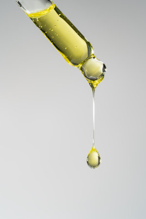 Pipette with serum, gel, oil or other cosmetic product with falling drop. Macro closeupの写真素材