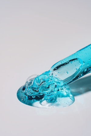 Pipette with serum, gel, oil or other cosmetic product with falling drop. Macro closeup