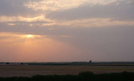 Orange sunray, gray clouds, horizon, valley and silhouette. A sunset image for nature theme background with copy space for texts or messages.の写真素材