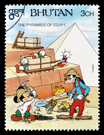 Cancelled postage stamp printed by Bhutan, that shows Mickey Mouse and Goofy, visiting Pyramids, circa 1991.のeditorial素材