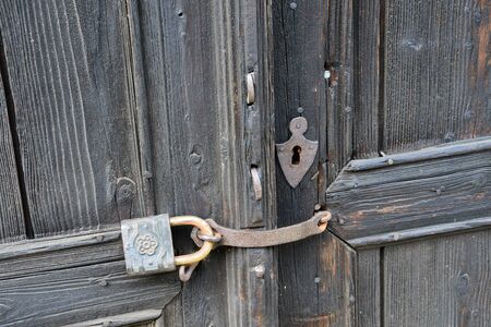 Antique metal padlock on a wooden door