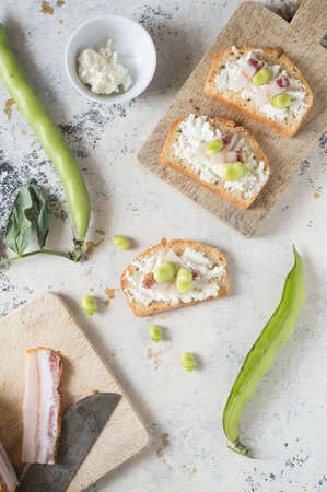 Three italian bruschetta with ricotta cheese, italian pancetta and broad beans. White background.の写真素材