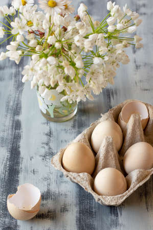 Eggs in a box on a white and gray background. White flowers in the back.の写真素材