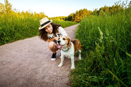 Girl with a beagle on a path in the grass.の写真素材