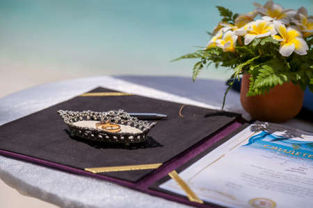 Wedding rings and wedding certificate on a tropical wedding on the background of the sea.の写真素材