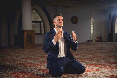 Young Muslim man praying in a mosque.