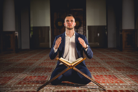Young Muslim man praying in a mosque.