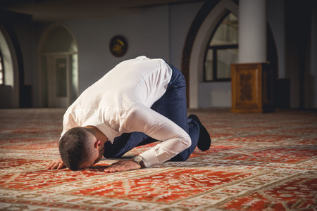 Young Muslim man praying in a mosque.