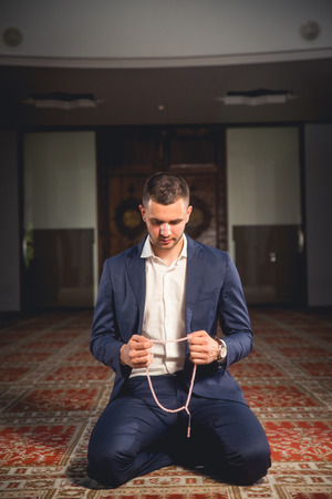 Young Muslim man praying in a mosque.の写真素材