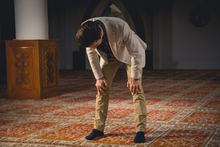 Young Muslim man praying in a mosque.