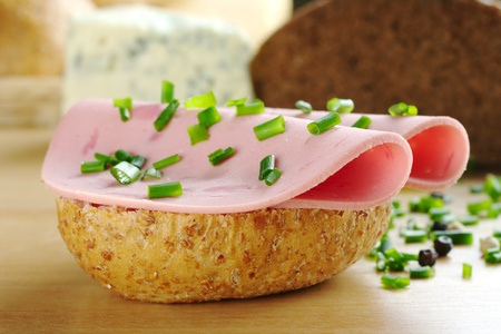 Open wholewheat sandwich with two slices of cold cut and chives. Peppercorns, bread and cheese in the background (Selective Focus, Focus on the front of the sandwich)の写真素材