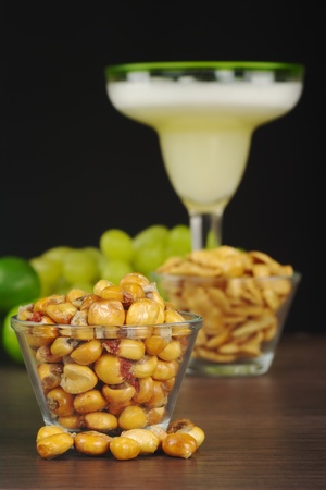 Canchas: Peruvian roasted corn eaten as snack with the cocktail called Pisco Sour in the back with limes and grapes (Selective Focus, Focus on the front) の写真素材