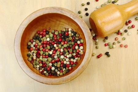 Black, red, green and white peppercorns in wooden mortar with pestle on wooden board photographed from above (Selective Focus, Focus on the peppercorns in the mortar)の写真素材