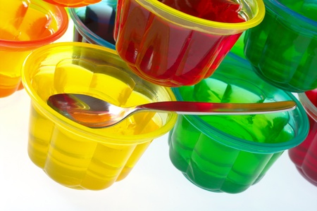 Colorful jellies in plastic bowls arranged in a pile with a teaspoon (Selective Focus, Focus on the teaspoon) の写真素材