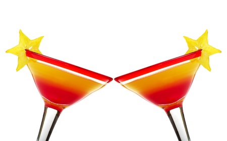 Toasting with Tequila Sunrise in red-rimmed cocktail glass garnished with a star-fruit slice on white (Selective focus)の写真素材
