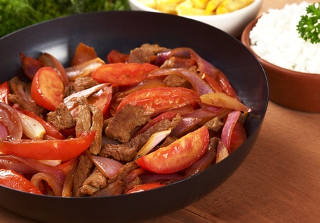 Preparing the Peruvian dish called Lomo Saltado in frying pan (beef, tomato and onions). It is served with French fries and rice. (Selective Focus, Focus on the middle of the pan)の写真素材
