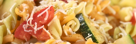 Colorful fusilli pasta with zucchini, tomato and grated cheese (Selective Focus, Focus on the outer side of the tomato)の写真素材