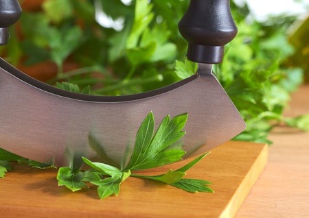 Fresh parsley leaves with a mezzaluna (Selective Focus, Focus on the parsley leaf in front of the...
