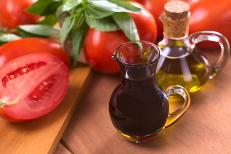 Balsamic vinegar with olive oil, tomato and basil in the background (Selective Focus, Focus on the front of the rim of the vinegar bottle) の写真素材