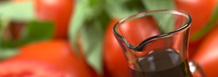 Balsamic vinegar with tomato and basil in the back (Very Shallow Depth of Field, Focus on the front of the bottle rim)の写真素材