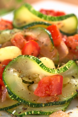 Sauteed zucchini slices, tomato cubes, onion and cooked corn grains with dried herbs and black pepper (Selective Focus, Focus on the upper part of the zucchini slice and the tomato cube below)の写真素材