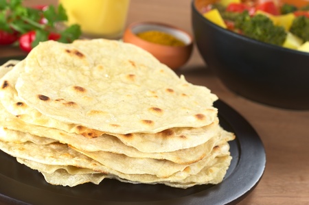 Indian flatbread called Chapati with vegetable curry, curry and mango lassi in the back (Selective...