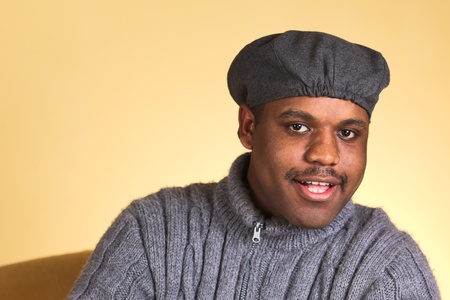 Portrait of a smiling young man of African descent sitting on a sofa (Selective Focus, Focus on the...