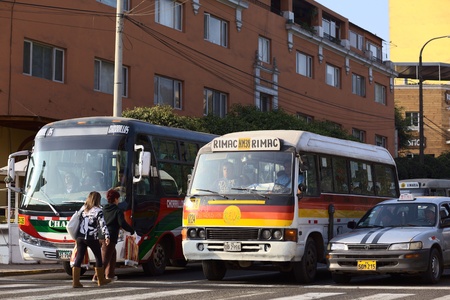 Lima, Peru - September 13, 2011: Buses and a taxi standing at red light and two women getting on the bus. Buses and taxis are the main means of transportation in Lima. There are many new regulations to achieve less accidents on the streets of the Peruvianのeditorial素材