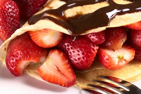 Crepe filled with fresh strawberries and chocolate sauce on top (Selective Focus, Focus on the strawberry cut on the left and the front of the two strawberries beside)の写真素材
