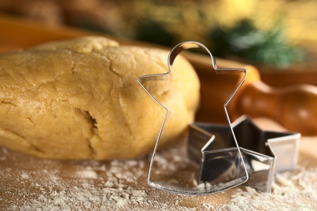 Angel-Shaped cookie cutter with cookie dough and rolling pin in the back (Selective Focus, Focus on the angel-shaped cutter)の写真素材