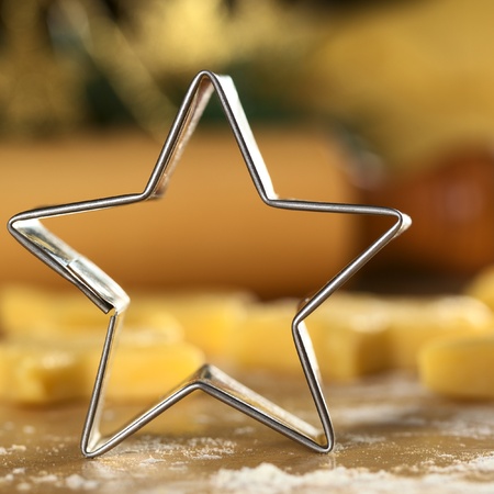 Star-shaped cookie cutter with raw cookies and rolling pin in the back (Selective Focus, Focus on the front edge of the cutter)  の写真素材