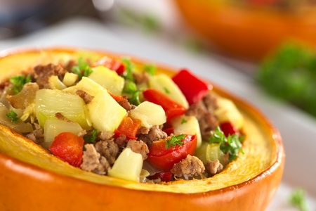 Stuffed baked pumpkin filled with zucchini, red bell pepper, minced meat, onions and garnished with parsley (Selective Focus, Focus one third into the stuffing)の写真素材