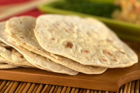Indian flatbread called chapati on wooden board (Selective Focus, Focus on the front of the first three chapatis)の写真素材