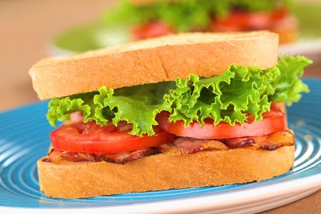 Fresh homemade BLT (bacon lettuce and tomato) sandwich on blue plate (Selective Focus, Focus on the...