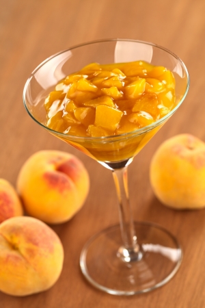 Fresh peach compote in cocktail glass on wood (Selective Focus, Focus one third into the glass) の写真素材